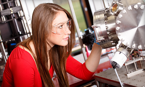 Young woman inspecting laser equipment in lab