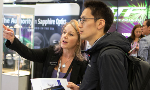 Two people discuss technology at Photonex exhibition