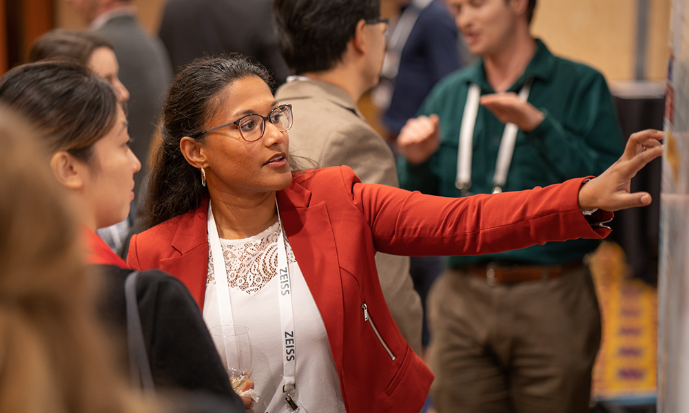 A woman shows her poster presentation at Laser Damage