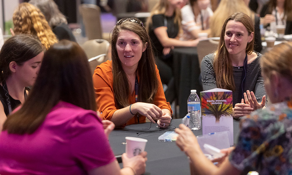 Several females sit at a table discussing technology at Photonics West
