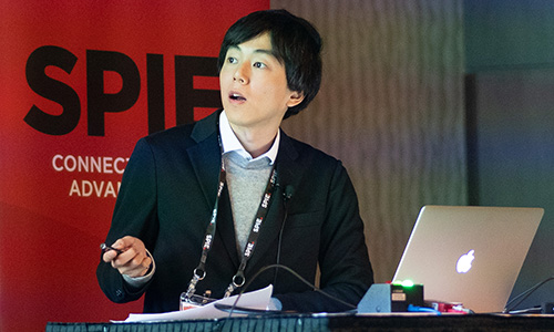 Conference speaker presenting research at Photonex