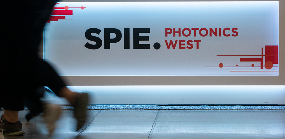 SPIE-branded sign and people walking at 2022 SPIE Photonics West.